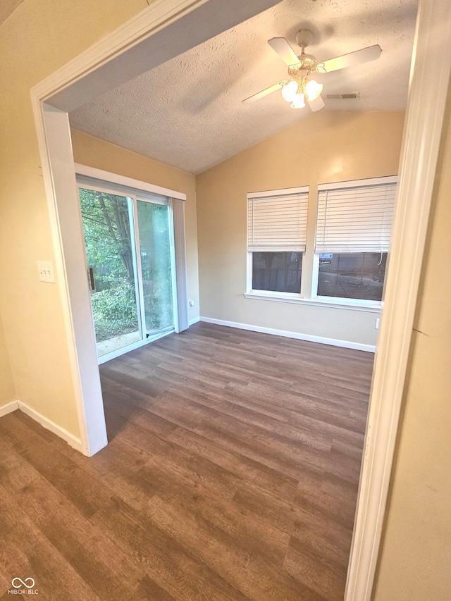 spare room featuring vaulted ceiling, dark hardwood / wood-style flooring, ceiling fan, and a textured ceiling