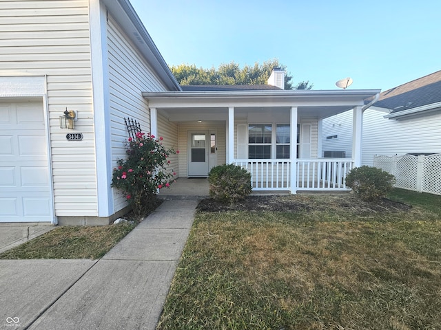 property entrance with a garage, covered porch, and a yard