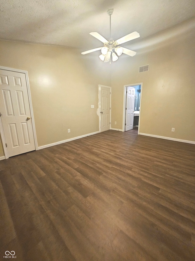 unfurnished room with ceiling fan, a high ceiling, dark wood-type flooring, and a textured ceiling