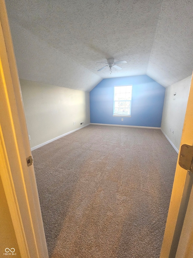 additional living space with ceiling fan, carpet flooring, a textured ceiling, and lofted ceiling