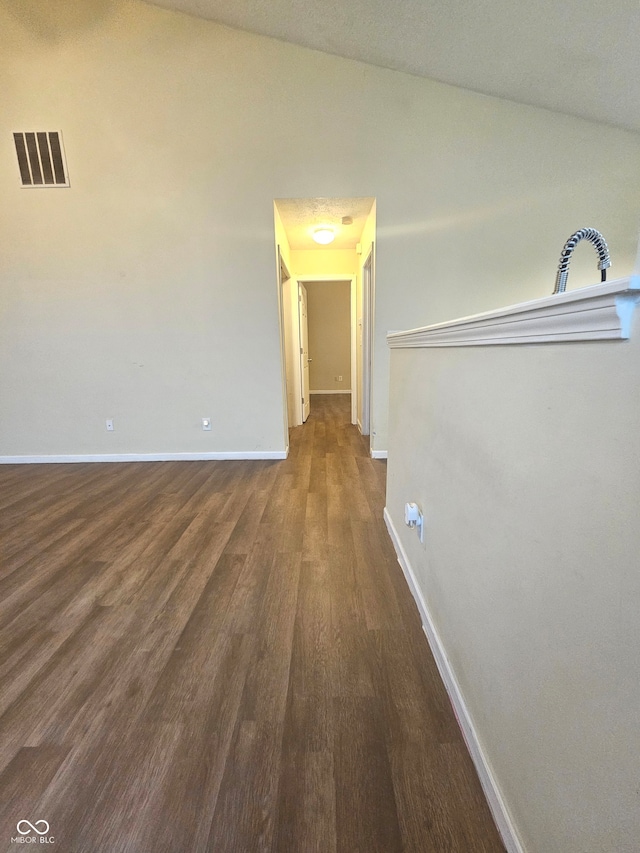 corridor featuring dark wood-type flooring and vaulted ceiling