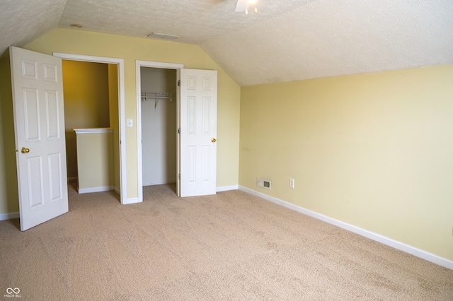 unfurnished bedroom featuring lofted ceiling, a textured ceiling, a closet, and ceiling fan