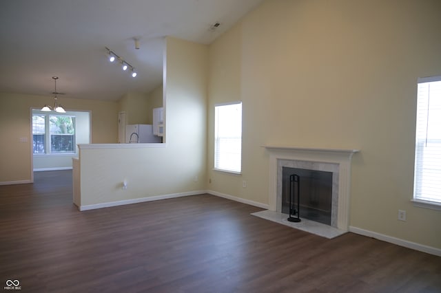 unfurnished living room with plenty of natural light, dark hardwood / wood-style floors, a fireplace, and rail lighting