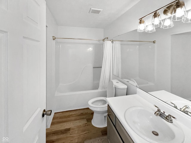 bathroom with toilet, shower / tub combo with curtain, vanity, wood finished floors, and a textured ceiling
