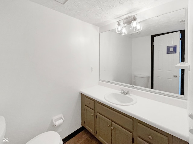 bathroom with vanity, toilet, and a textured ceiling