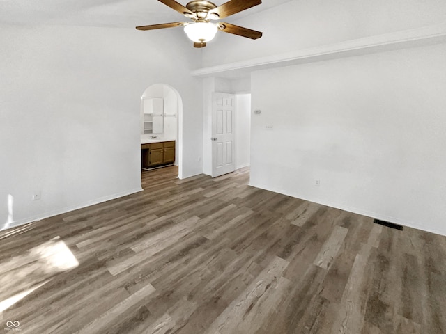 empty room featuring arched walkways, ceiling fan, and wood finished floors