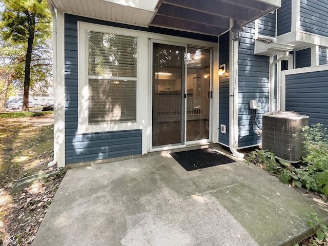 view of exterior entry with central air condition unit and a patio