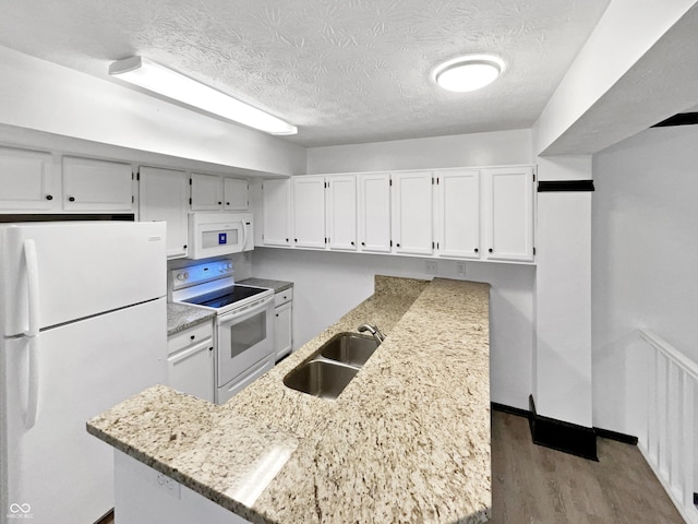 kitchen featuring white appliances, light stone countertops, white cabinetry, a sink, and radiator