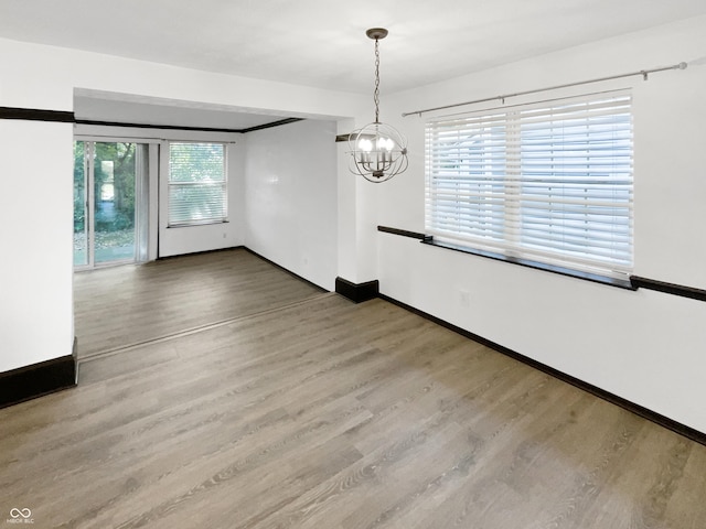 unfurnished dining area featuring baseboards, wood finished floors, and a chandelier