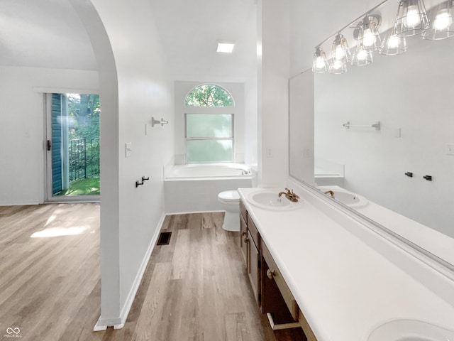 full bath with a sink, a garden tub, wood finished floors, visible vents, and double vanity