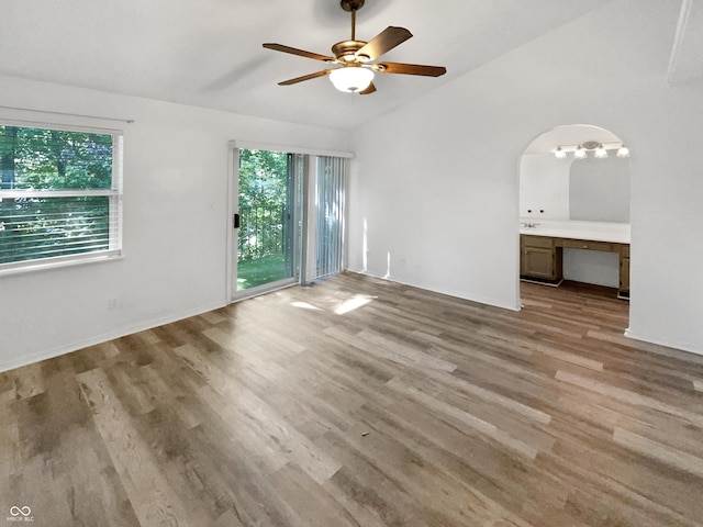 unfurnished bedroom with multiple windows, access to exterior, vaulted ceiling, and wood finished floors