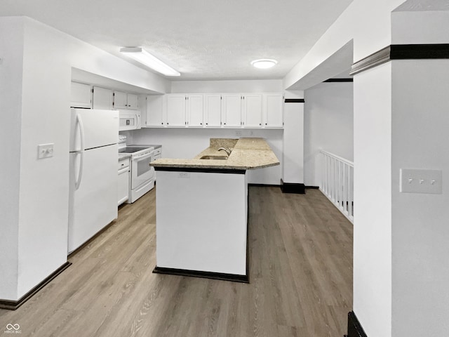 kitchen with white cabinets, a sink, light wood-style floors, and white appliances