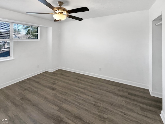 spare room featuring dark wood-type flooring, ceiling fan, and baseboards