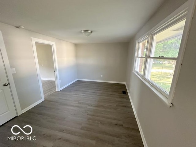 spare room featuring dark wood-type flooring and baseboards