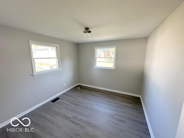 spare room with dark wood-style floors, baseboards, and visible vents