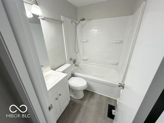 bathroom with visible vents, toilet, bathing tub / shower combination, wood finished floors, and vanity