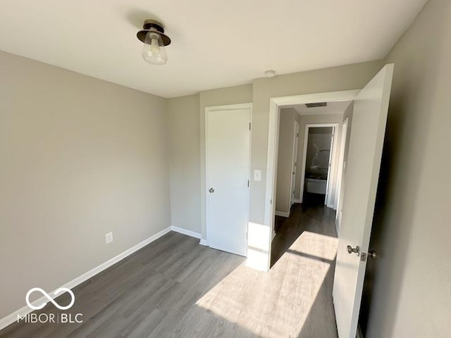 unfurnished bedroom featuring dark wood finished floors, visible vents, and baseboards