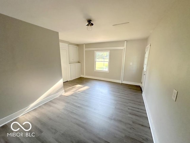 unfurnished room with baseboards and dark wood-style flooring