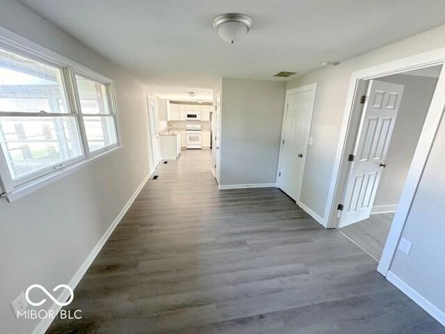 corridor with visible vents, baseboards, and dark wood finished floors