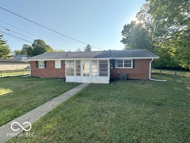 rear view of property featuring a yard, brick siding, central AC, and a sunroom