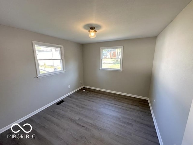 spare room with visible vents, baseboards, and dark wood-style floors