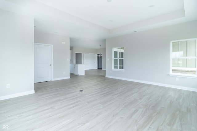 unfurnished living room featuring a chandelier and light wood-type flooring