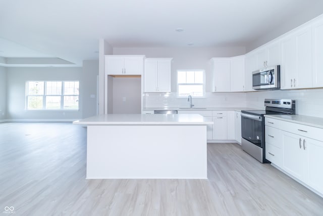 kitchen featuring a wealth of natural light, a center island, white cabinets, and appliances with stainless steel finishes