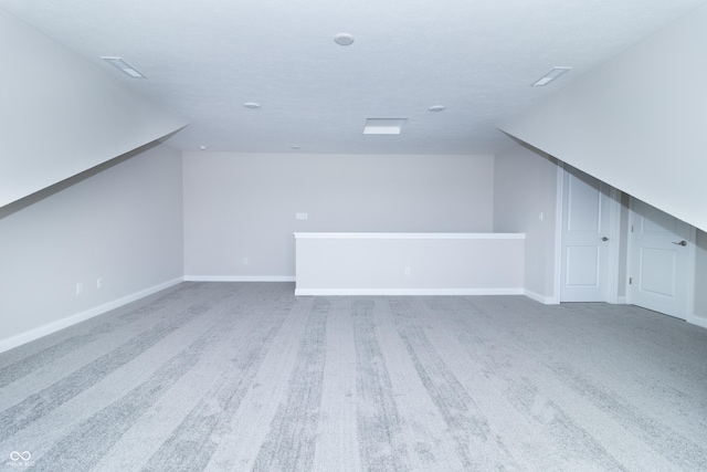 bonus room featuring carpet flooring and a textured ceiling