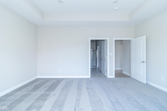 unfurnished bedroom featuring carpet and a tray ceiling