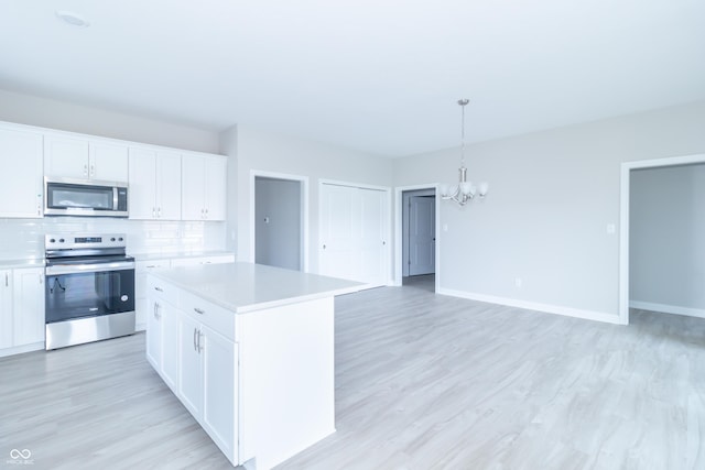 kitchen featuring pendant lighting, a kitchen island, white cabinetry, and stainless steel appliances