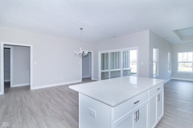 kitchen with decorative light fixtures, light hardwood / wood-style flooring, a chandelier, a center island, and white cabinetry