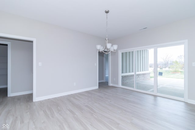 empty room with a chandelier and light hardwood / wood-style flooring