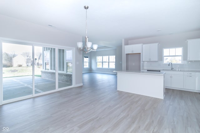 kitchen featuring white cabinets, a healthy amount of sunlight, light wood-type flooring, and a kitchen island