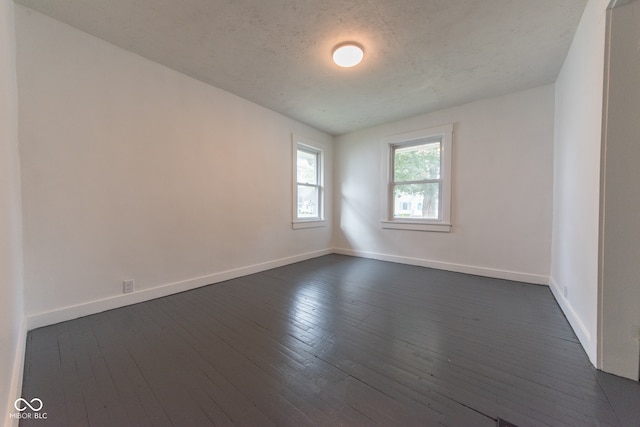 empty room featuring a textured ceiling and dark hardwood / wood-style flooring