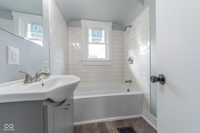 bathroom featuring vanity, hardwood / wood-style floors, tiled shower / bath combo, and a wealth of natural light