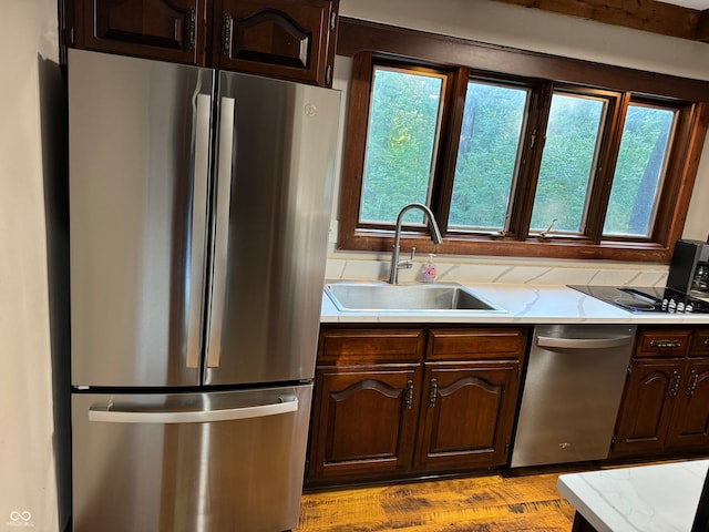 kitchen with appliances with stainless steel finishes, a wealth of natural light, light hardwood / wood-style flooring, and sink