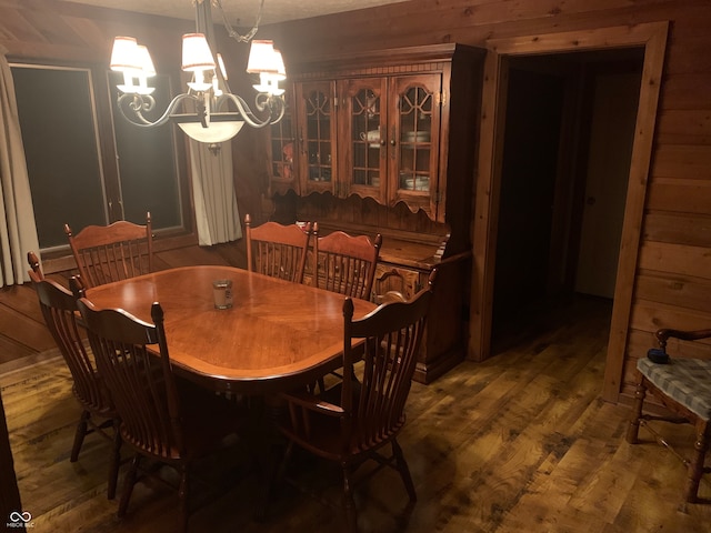 dining space featuring wood walls, a notable chandelier, and dark hardwood / wood-style floors