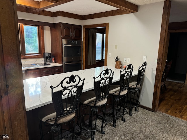 dining space featuring wood-type flooring, beamed ceiling, and a textured ceiling