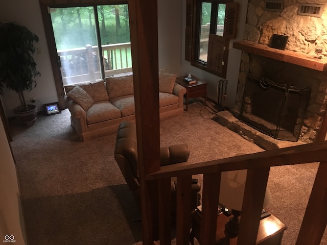 living room featuring a wealth of natural light, radiator, carpet floors, and a stone fireplace