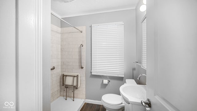 bathroom with a textured ceiling, toilet, hardwood / wood-style flooring, and a tile shower