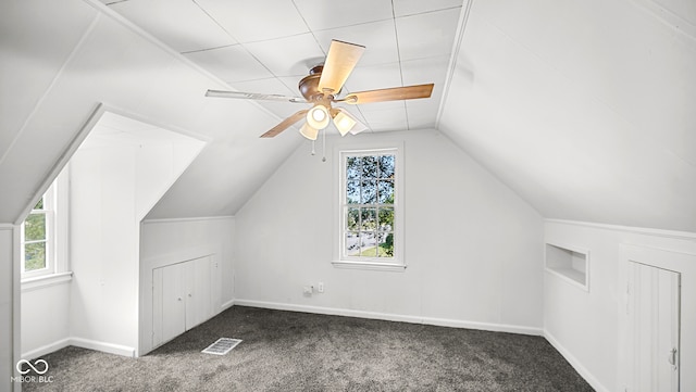 additional living space featuring lofted ceiling, plenty of natural light, dark colored carpet, and ceiling fan