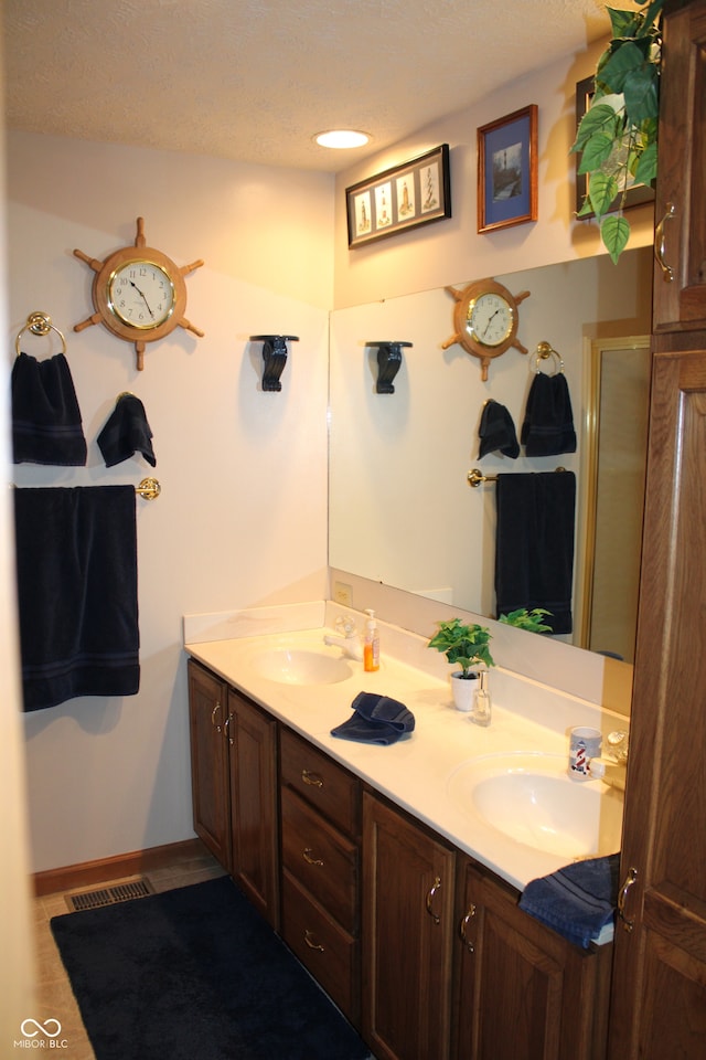 bathroom with an enclosed shower, vanity, and a textured ceiling