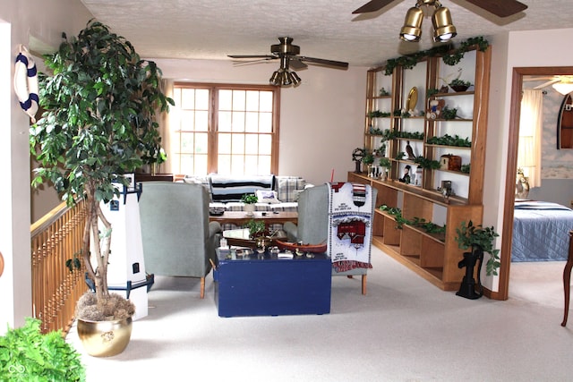 living area featuring carpet flooring, a textured ceiling, and a ceiling fan