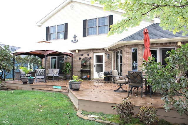 back of property featuring a lawn, brick siding, roof with shingles, and a wooden deck