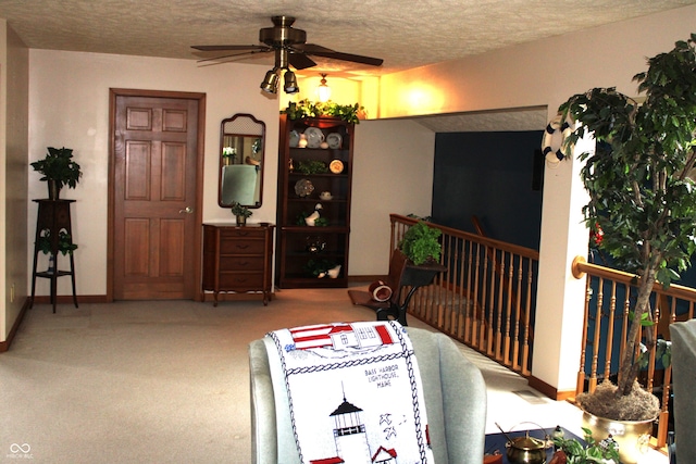 carpeted living area featuring ceiling fan, baseboards, and a textured ceiling