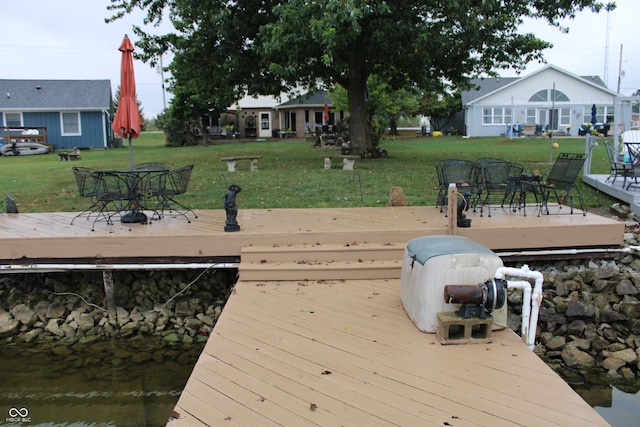 view of dock with outdoor dining area and a lawn