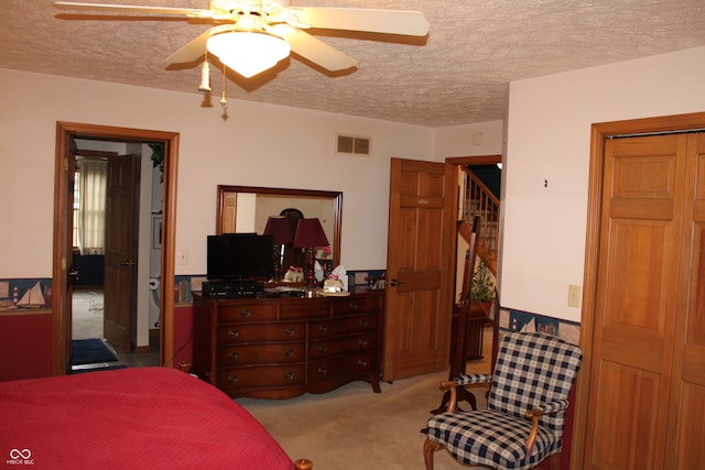 bedroom with a textured ceiling, ceiling fan, and light colored carpet