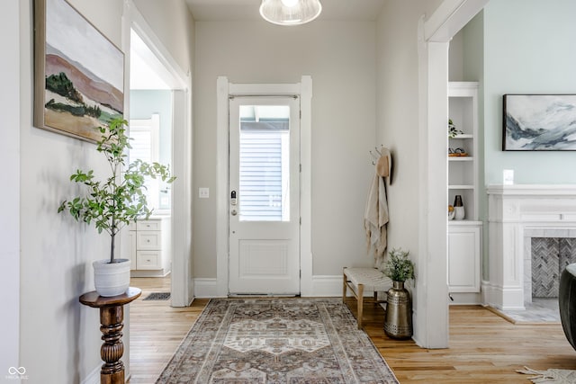 1715 Alabama St, Indianapolis, IN 46202 - entryway featuring light wood-style flooring, a tiled fireplace, and baseboards