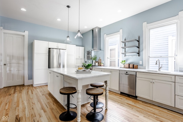 1715 Alabama St, Indianapolis, IN 46202 - kitchen with stainless steel appliances, a sink, light wood-style floors, white cabinetry, and wall chimney range hood