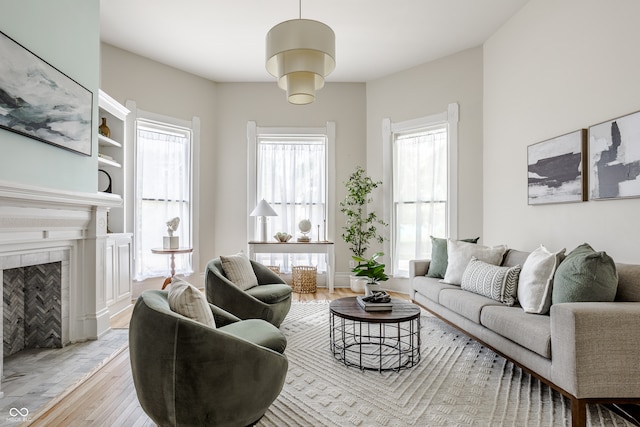 living room with a tile fireplace, plenty of natural light, and light hardwood / wood-style floors